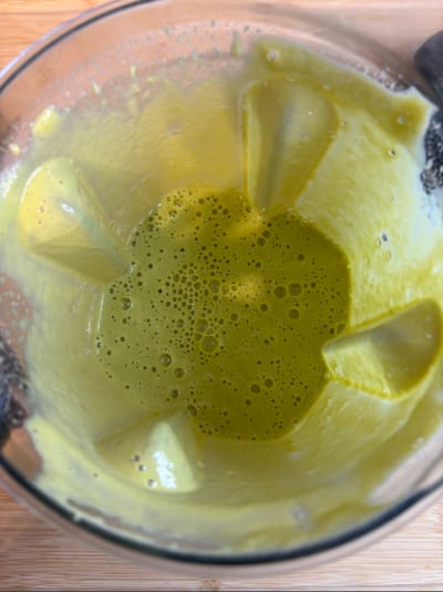 Frothy green smoothie inside blender jar