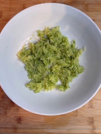 Grated zucchini in white bowl
