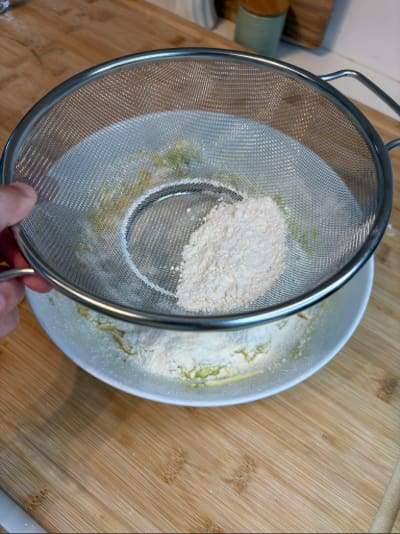Hand sifting flour into mixing bowl