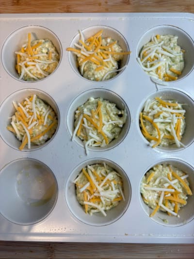 Muffin tin filled with cheesy corn muffin batter
