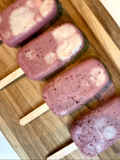 Berry yogurt swirl popsicles on wooden board
