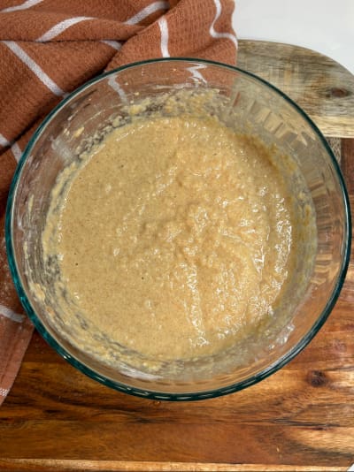 Glass bowl of batter on wooden cutting board
