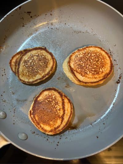Three golden-brown pancakes in frying pan
