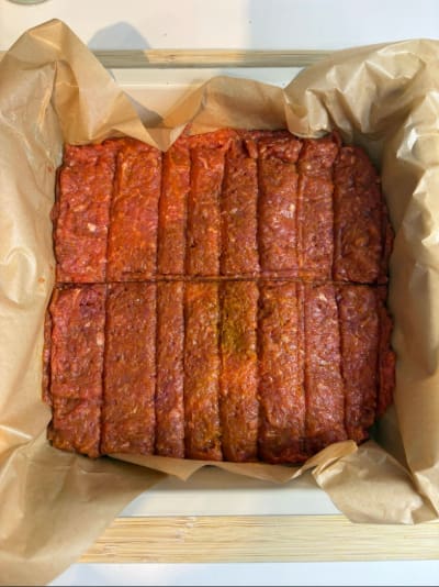 Raw seasoned meatloaf scored in baking dish